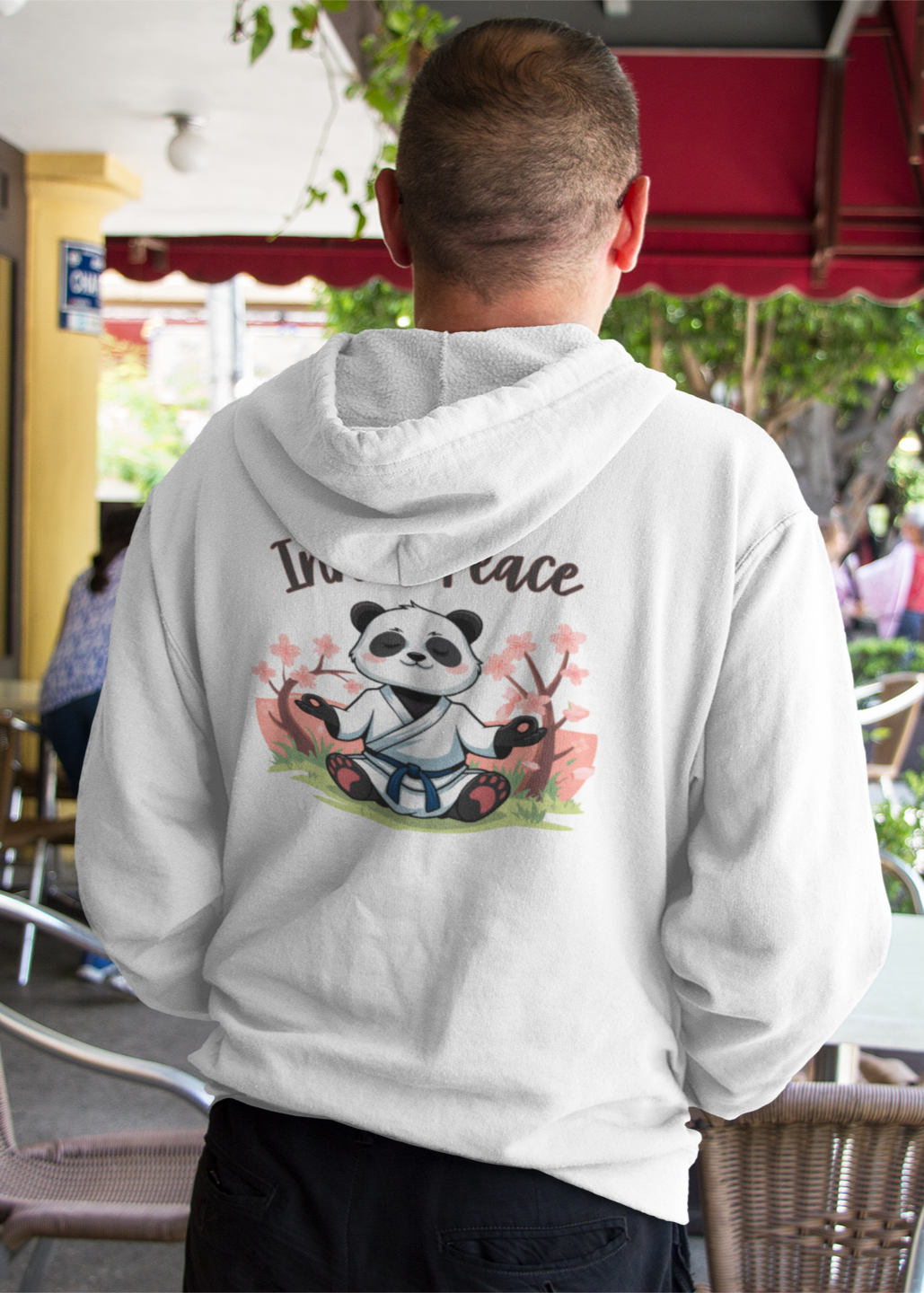 Person wearing a white hoodie with a panda design in an outdoor setting